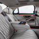 the interior of the 2023 mercedes-amg s 63 e performance sedan, seen from the right-rear seat. the upholstery is dove grey and orange accent lighting emanates from the doors and center console.